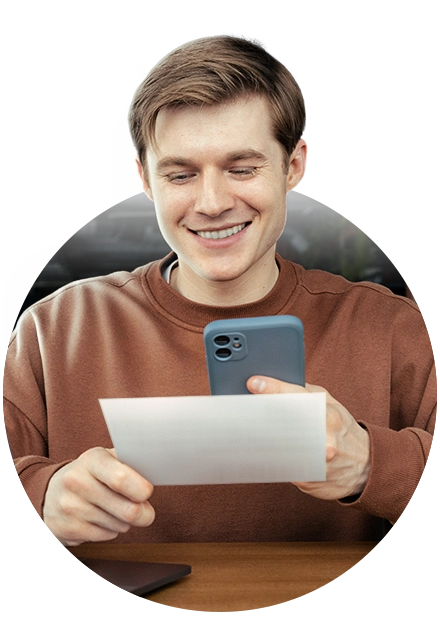 homem com celular apontado para papel em suas mãos, representando pagamento por boleto bancário
